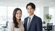© Yka - オフィスで微笑みながら立つ男女