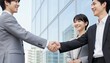 © Yka - ビルの前で握手をするビジネスパーソン