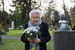 © Halfpoint - Elderly woman visiting a grave on All Saints Day.