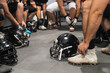 © Koldo_Studio - American football players getting ready in a locker room, putting on cleats and tying laces, with helmets on floor