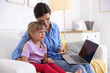 © New Africa - Telehealth. Mother and her sick daughter having online consultation with doctor via laptop on sofa at home