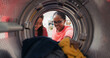 © ABCreative - A cheerful daughter helps her mom with the laundry, holding clothes in her hands while the woman opens the washing machine drum, they enjoy spending time together.