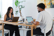 © Studio Marmellata - Two young professionals work on laptops at a modern office desk. The woman smiles while typing, and the man focuses on his screen. They collaborate in a bright workspace.