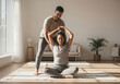 © Yash - Man assisting woman in seated yoga stretch