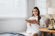 © Phimwilai - Young woman reading a book at home in living room