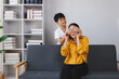 © Phimwilai - Asian son surprising mother by covering her eyes on sofa at home