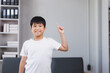 © Phimwilai - Smiling asian boy pointing up with finger in living room