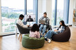 © sofiko14 - Group of multiracial coworkers, including disabled male, engaged in team meeting using video conference with male manager displayed on screen, embracing modern teamwork solutions in a casual office.