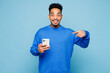 © ViDi Studio - Young man of African American ethnicity wear sweatshirt casual clothes hold in hand use point finger on mobile cell phone isolated on plain pastel light blue cyan background studio. Lifestyle concept.
