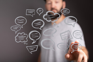 Concept of social media interaction and online communication with a man touching virtual speech bubbles for ideas. Online communication concept
