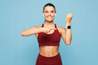 © ViDi Studio - Young fitness trainer instructor sporty woman sportsman in red sportswear headphones training in home gym use blank screen smart watch isolated on plain blue background Workout sport fit abs concept