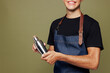 © ViDi Studio - Cropped young man barista bartender barman employee wear jeans apron t-shirt work in night club hold shaker for preparing cocktails isolated on plain green background. Small business startup concept.