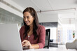 © fizkes - Smiling woman working on laptop in office