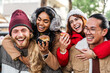 Happy friends having fun drinking mulled wine and hot chocolate at Christmas Market - Cheerful young people enjoying winter holidays on weekend vacation - Tourism lifestyle and friendship concept