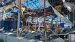 © Natalia_SL - Destroyed industrial building with collapsed roof and exposed metal framework. Piles of insulation material and debris on the ground. Explosion damage