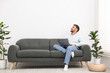 © New Africa - Man with laptop on sofa at home. Space for text