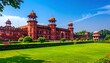 © Wndyy - Majestic historic palace with vibrant red sandstone architecture and sprawling green gardens under a clear blue sky