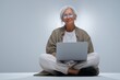 © Andrii Zastrozhnov - Elderly caucasian woman with laptop in casual attire sitting cross-legged on floor