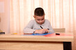 © Vasyl - A boy makes applications from colored paper while sitting at a table. The concept of creativity and leisure.