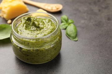 Wall Mural - Fresh pesto sauce in jar on grey table, closeup. Space for text