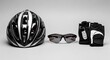 © Ulum - A black and white striped cycling helmet is displayed alongside sunglasses and fingerless gloves, all arranged on a neutral background.