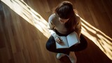 Reflective moments of creativity as a woman writes in her journal on a sunlit wooden floor
