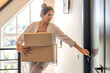 © puhimec - Woman with parcels reaching lock in modern loft, sunny moving vibes. One person, online shopping.