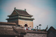 A weathered, grey stone building with traditional Chinese architecture lines a narrow Beijing street, showcasing aged textures and a glimpse of daily life within the capital.
