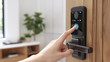 © saichon - Person using smart door lock with fingerprint scanner and digital keypad, enhancing home security