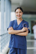 © crizzystudio - Young doctor smiling and holding stethoscope in hospital corridor