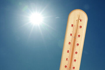 Wall Mural - thermometer showing high temperature against sky with bright sun. extremely hot weather