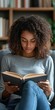 © Ilja - Young African American Woman Reading an Engaging Novel on a Cozy Couch in Her Home Environment
