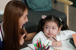 © itchaznong - Learning Together. Mother and daughter engaged in study session at home.