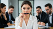 © Iryna - team in crisis with anxious female employee biting pen in tense office meeting, workplace stress and business conflict concept