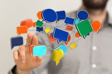 A man touching a digital network of colorful speech bubbles. Represents communication, networking, online interactions and social media connecti