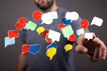 A man's hand touching a network of colorful speech bubbles, representing online communication and discussions.