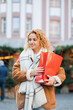© Kristina89 - Young woman holds a red bag in her hands, shopping for Christmas gifts at a holiday market.