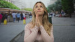 © Krakenimages.com - Blonde caucasian woman holds bare hands together in prayer at crowded outdoor market; faith hope serenity.