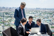 © chachamp - Business team working together on a laptop at outdoor or rooftop office with city background
