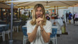 © Krakenimages.com - Man with long blond hair in a white t shirt clenches fists on an outdoor restaurant terrace under canvas umbrellas; excitement victory celebration triumph.