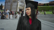 Graduated woman in black gown making expressions outdoors near the leaning tower in pisa city, capturing a blend of achievement and vibrant tourism background.