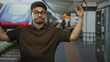 © Krakenimages.com - Man raising both hands in a questioning shrug gesture at a busy train station platform while wearing glasses and a brown polo; frustration.