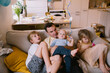 © nataliaderiabina - Father sitting on couch at home with his three children. Dad playing with his children on sofa. Domestic life, Real family and Life moments in living room.