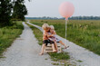© nataliaderiabina - Brother and sister sitting together on wooden box in countryside. Happy siblings in nature. Portrait of little girl and boy. Children birthday party, outdoor nature photoshoot with festive atmosphere.