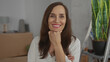 © Krakenimages.com - Woman smiling in a new home surrounded by moving boxes and a potted plant, portraying a sense of accomplishment and fresh beginnings indoors.