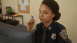 © Krakenimages.com - Hispanic woman police officer in uniform focusing at desk in indoor station office.