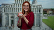 Woman enjoying strawberry ice cream in front of pisa cathedral on a sunny day features redhead lady smiling in italian city setting showcasing travel and leisure outdoors.