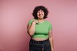 © bodnarphoto - Smiling person with curly hair wears a green shirt against a pink background in a cheerful indoor setting