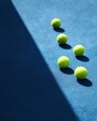 © Keattipoom - Bright Yellow Tennis Balls on Blue Court Surface with Sunlight and Shadow Effects in Sports Environment