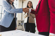 © Wasan - Businesswoman shaking hands with colleague after meeting in office. Business people shaking hands in the office for a deal, collaboration. Employees with handshake for welcome or greeting.